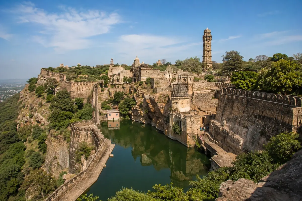 Panoramic view of Chittorgarh Fort featuring ancient fortifications, Vijay Stambh, historic temples, and a tranquil water reservoir surrounded by rugged landscapes in Rajasthan.