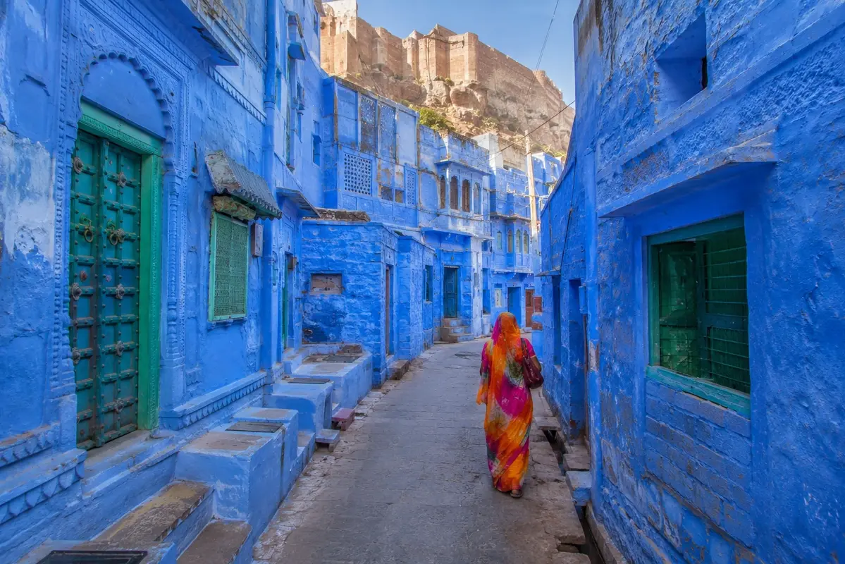 Colorful blue-painted streets of Jodhpur with traditional houses and Mehrangarh Fort rising above the Blue City.