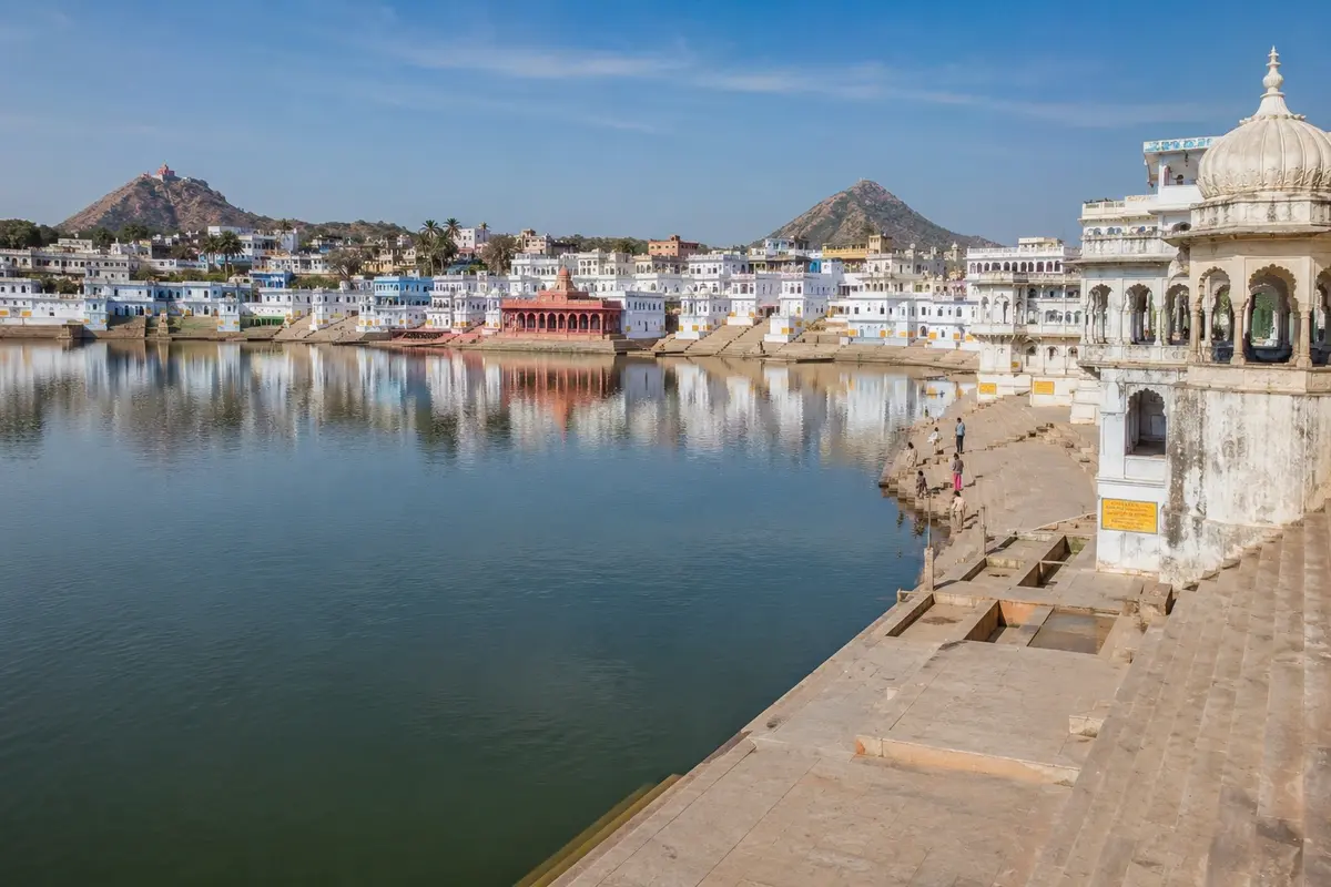 Panoramic view of Pushkar Lake surrounded by historic ghats, white temples, heritage buildings, and tranquil waters reflecting the spiritual atmosphere of Pushkar, Rajasthan.